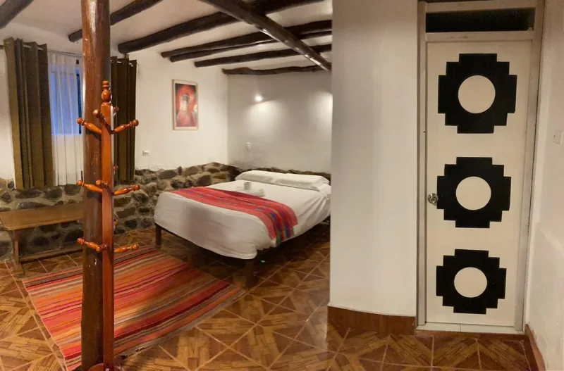 Interior de la habitación familiar 104 con textiles y vigas de madera